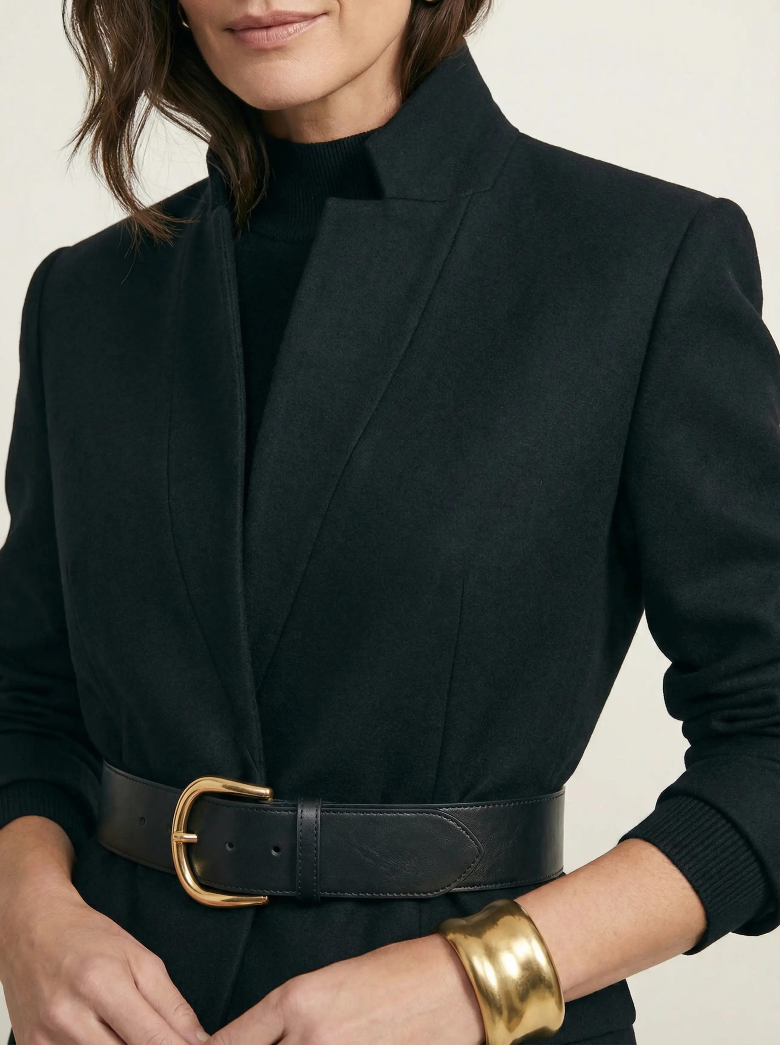Macro detail: chunky gold-buckled leather belt, wide gold cuff and textured high-collar knit.